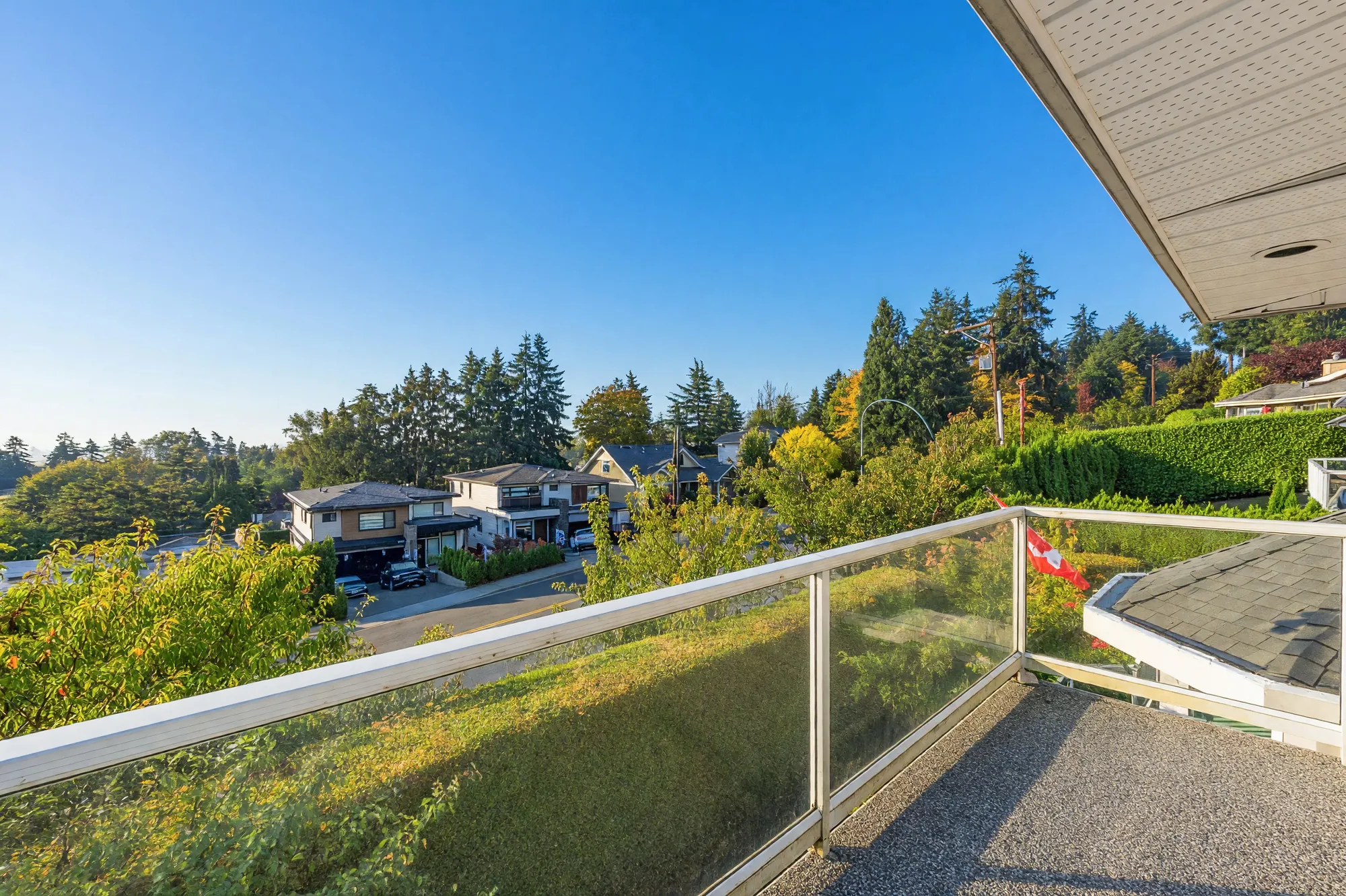 The balcony off the larger upper bedroom: glass railings, the road below and the farmland beyond