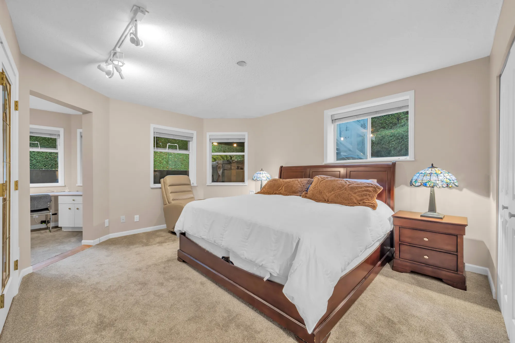 The larger lower bedroom: a bed, windows in an angled bay, an opening to the office