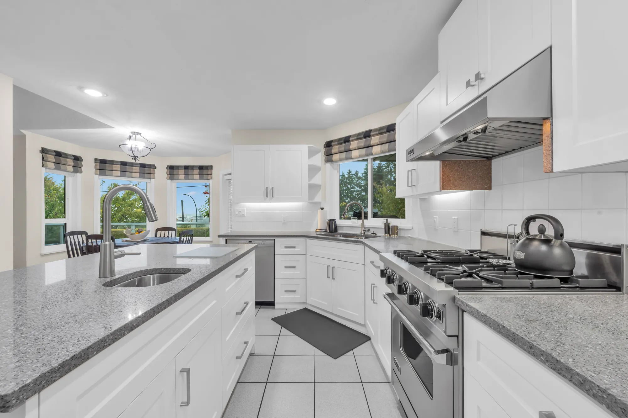 The island with the sink under the windows, the gas range and the hood at the right
