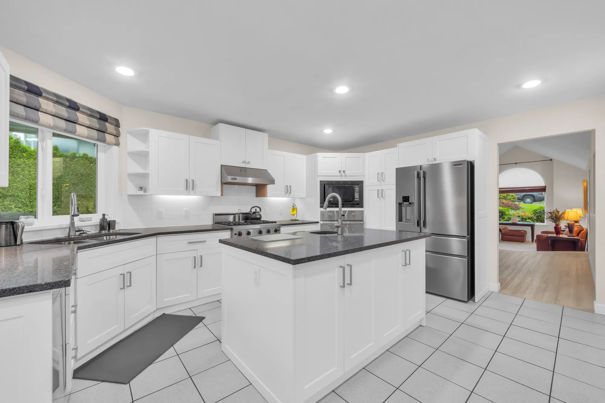 The kitchen from the breakfast nook: the island, a stainless fridge, a doorway to the dining room