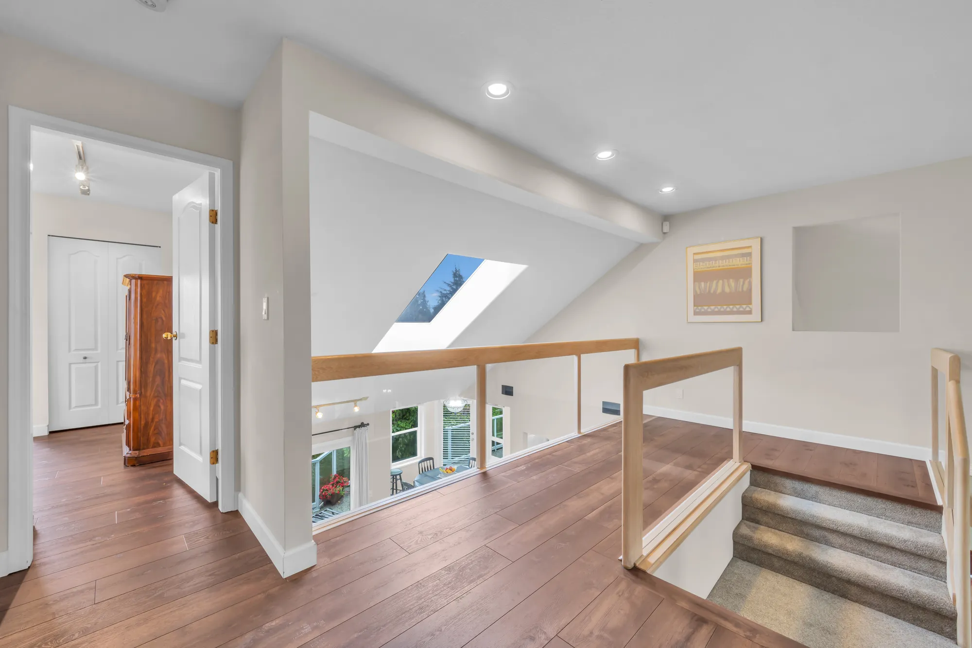 The upper hall: wood-look floors, a railing over the stair and the foyer below, a skylight