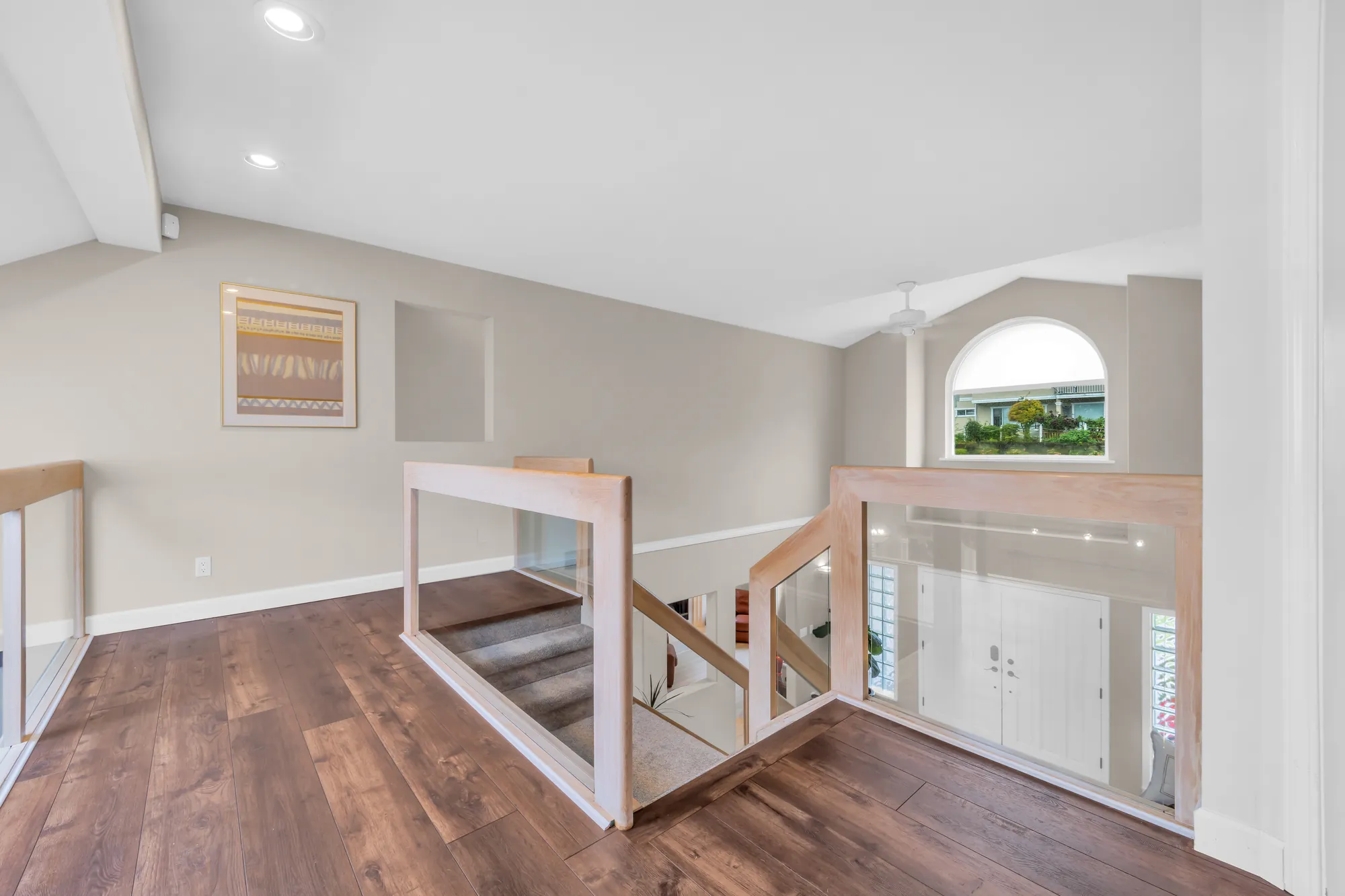 The upper hall toward the arched window over the entry, the railing and the stair