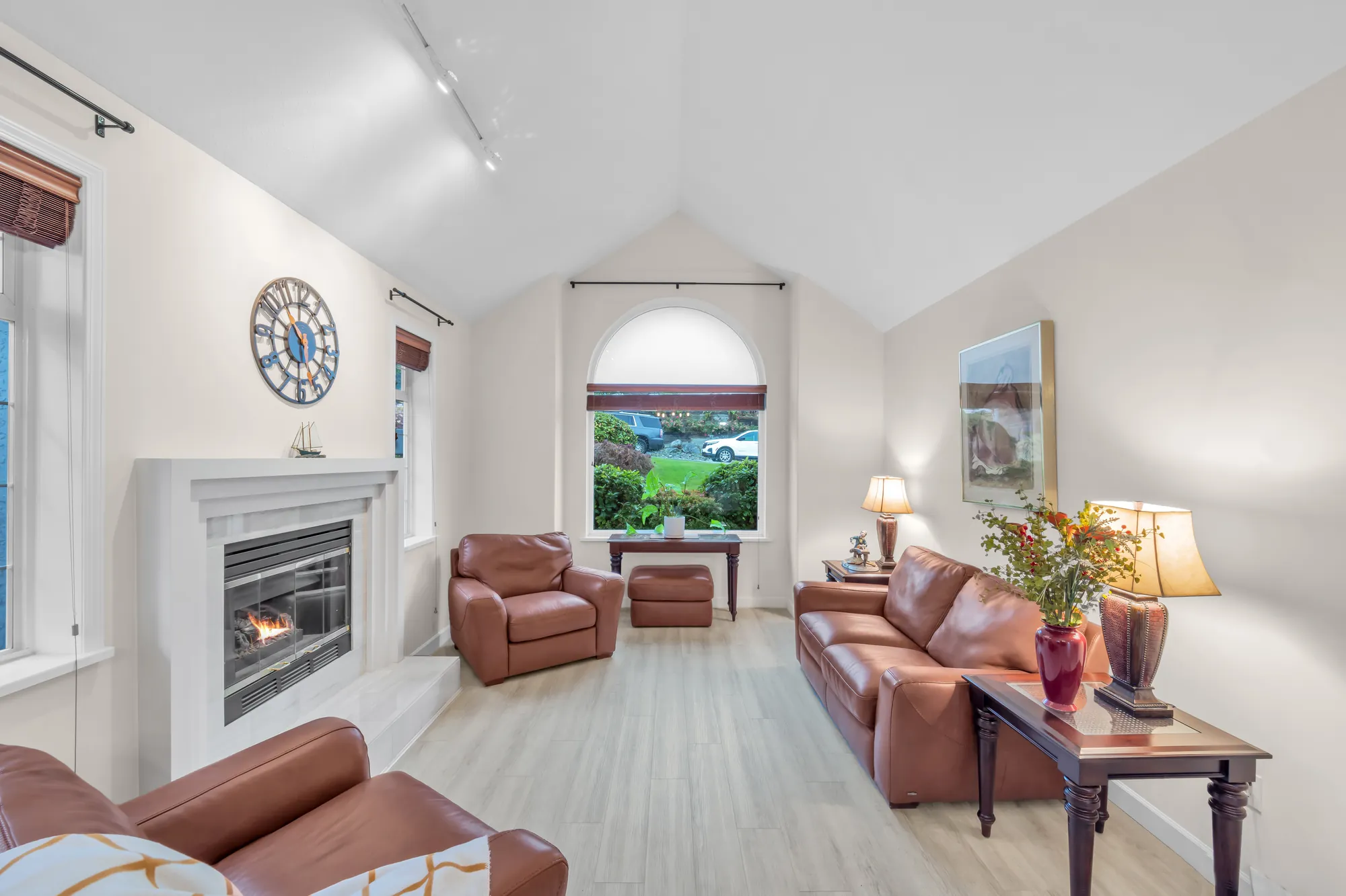 The living room toward the arched window and the fireplace, a sofa in the foreground