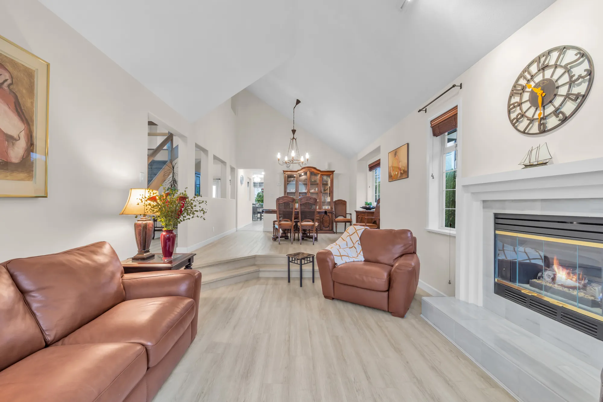 Across the living room to the dining room beyond, the fireplace at the right, a vaulted ceiling