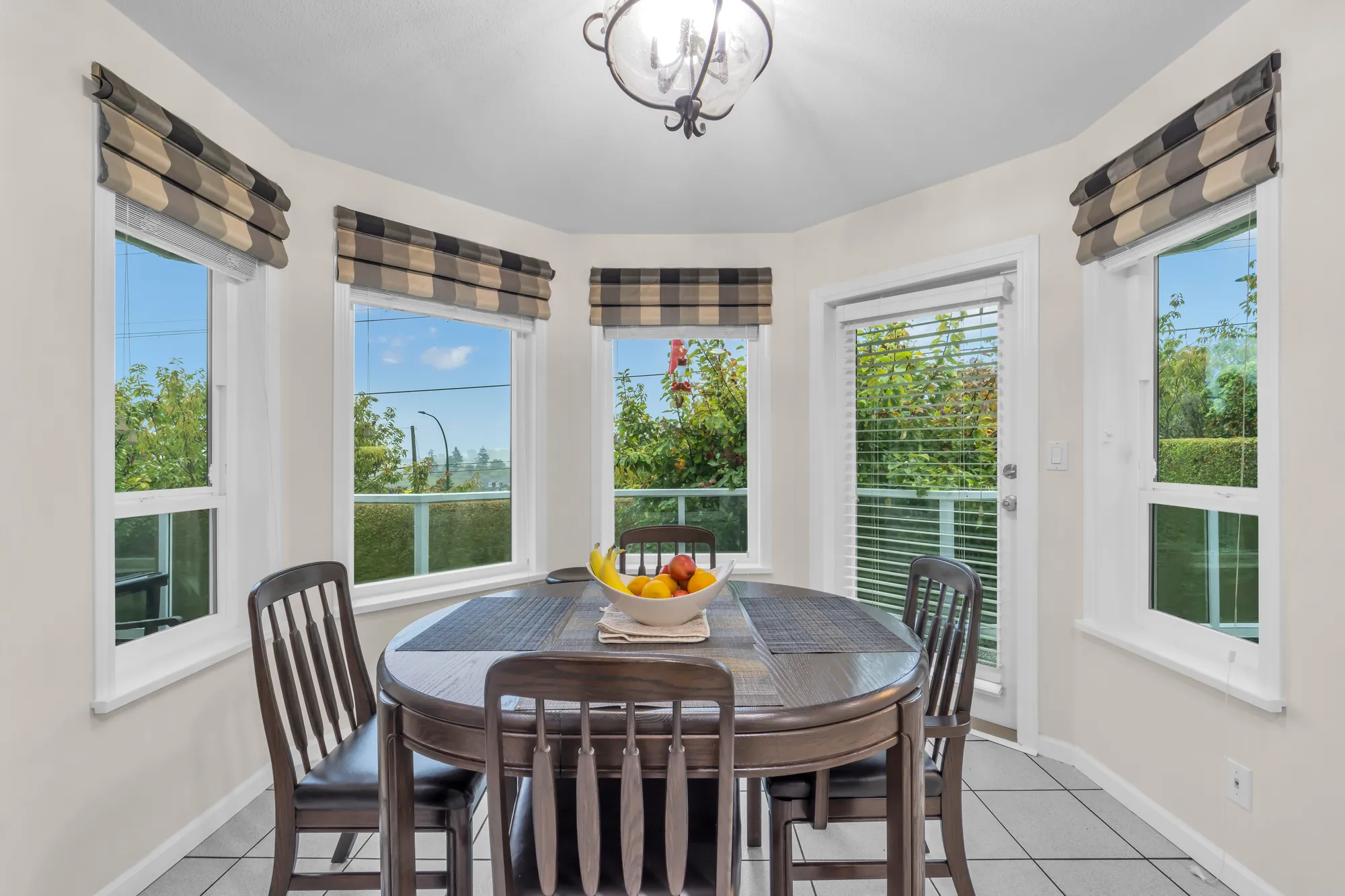 The breakfast nook: a round table and chairs in a bay of windows, a door with a blind to the deck