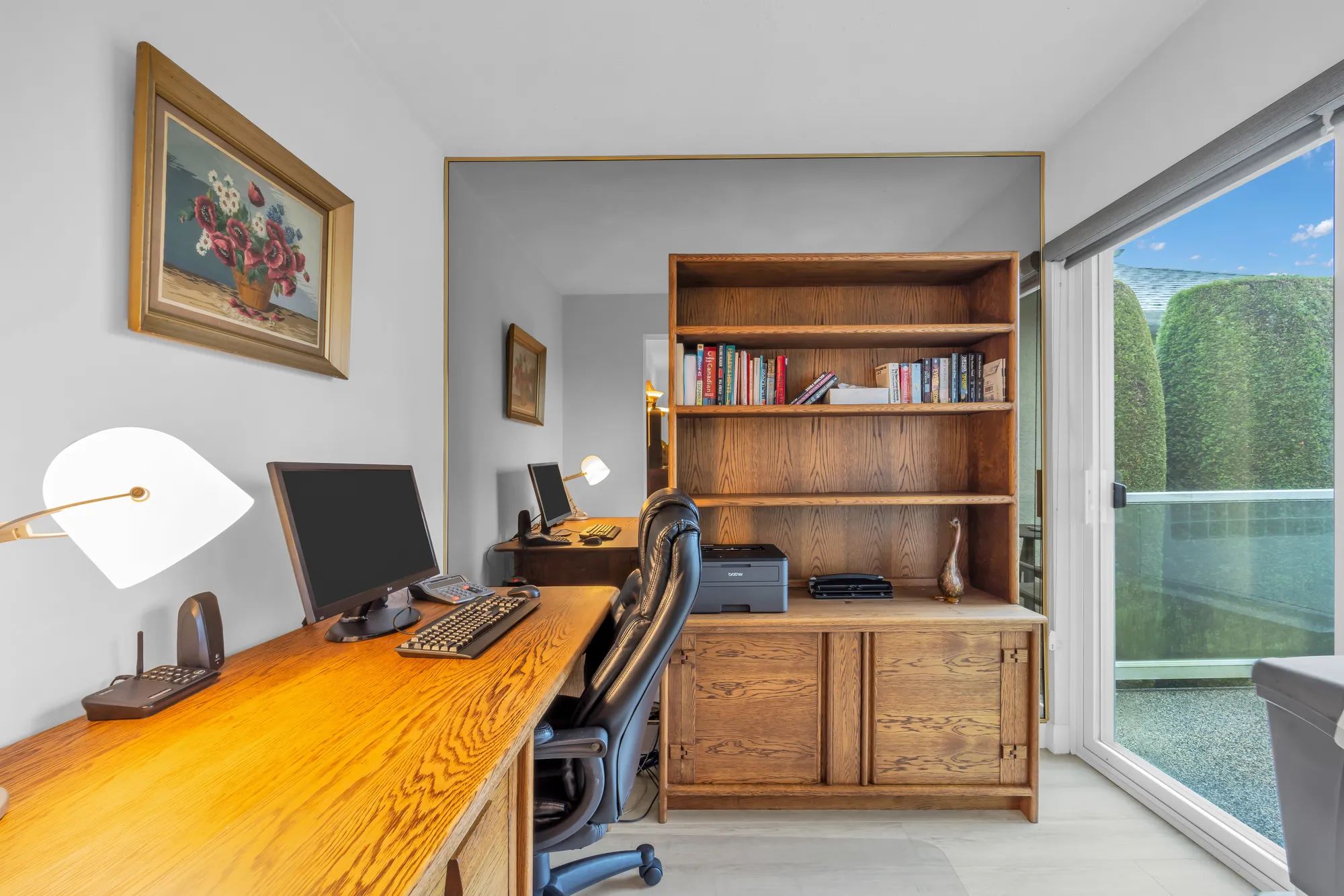 The office: a desk, a bookcase and a sliding door to a balcony with glass railings