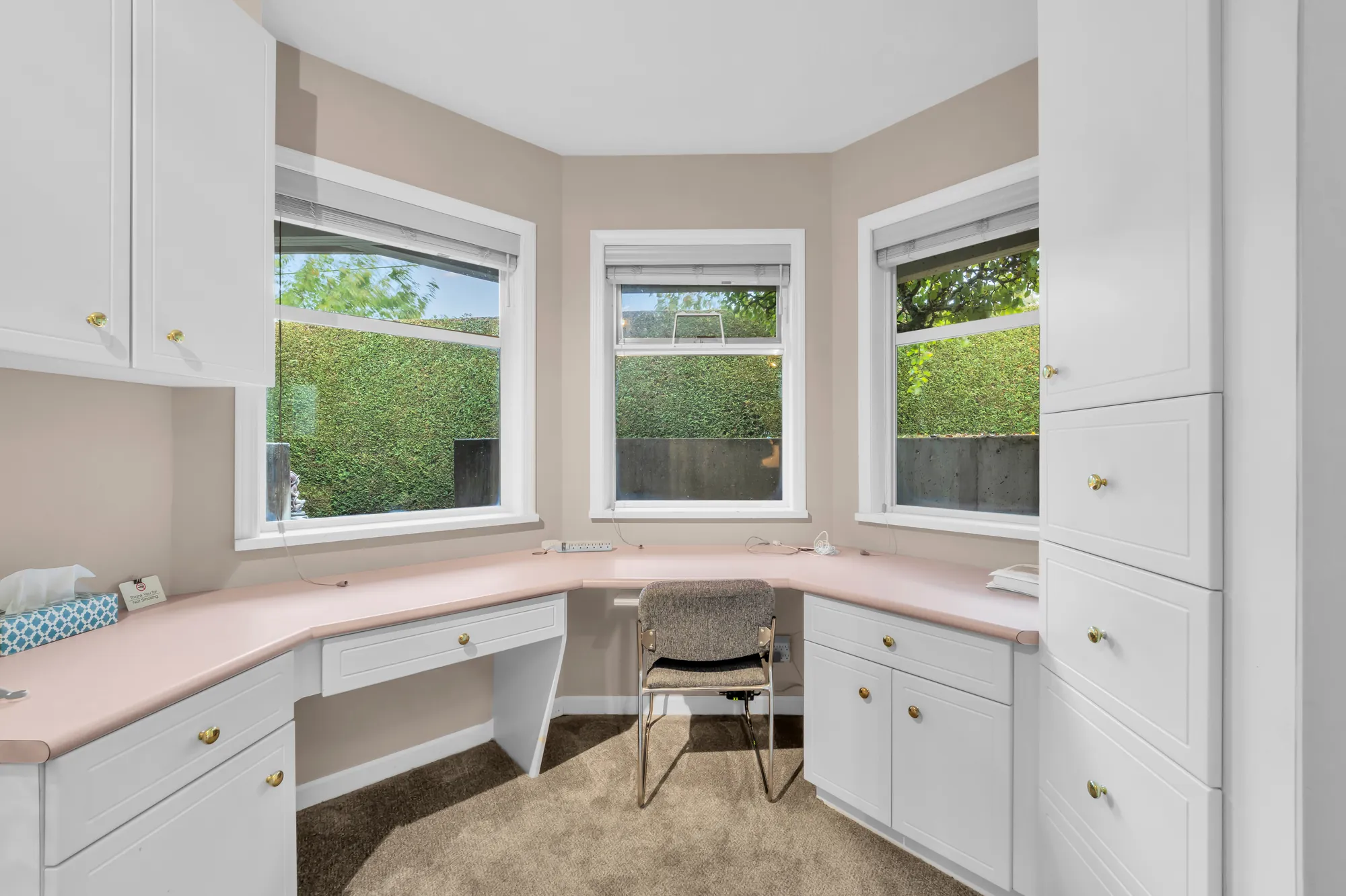 The lower office: built-in desks and cabinets in a bay of three windows