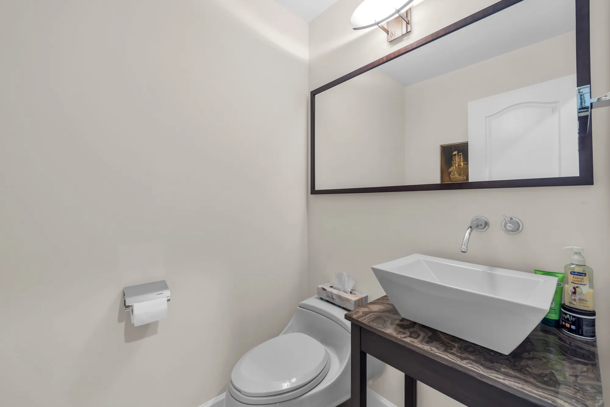 The powder room: a white vessel sink on a stone-topped stand, a wall-mounted tap, a large mirror