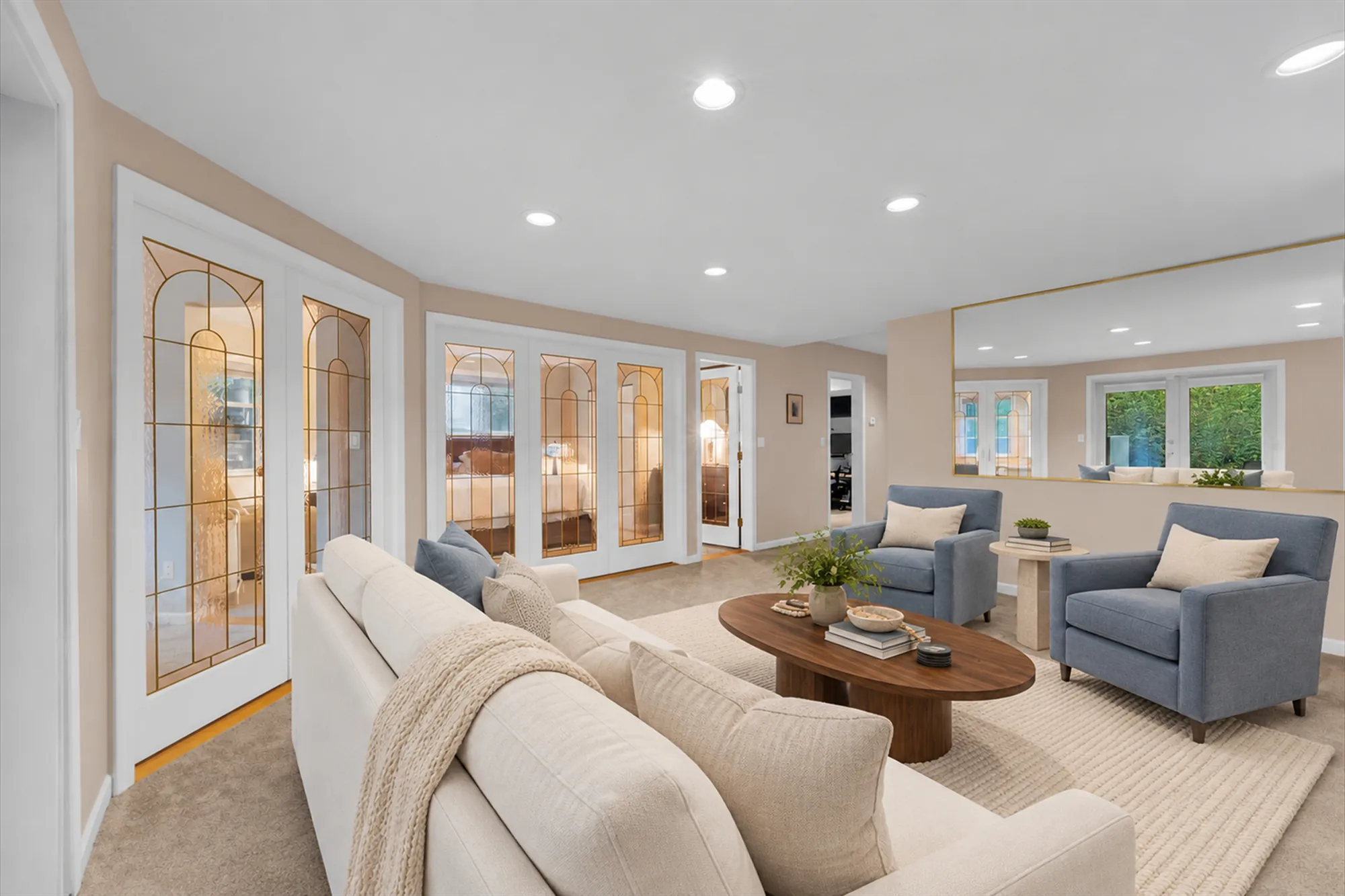 The same frame virtually staged: a cream sofa, two blue armchairs, an oval wood coffee table, a stone side table, a rug